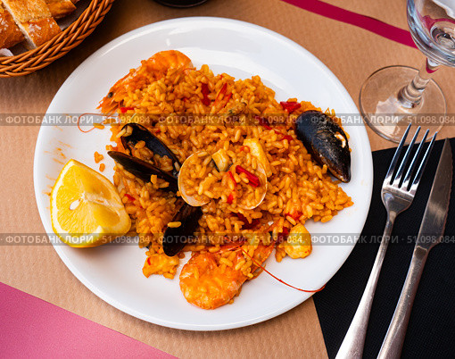 Paella made of rice and different seafood served in plate with table appointments. Стоковое фото, фотограф Яков Филимонов / Фотобанк Лори