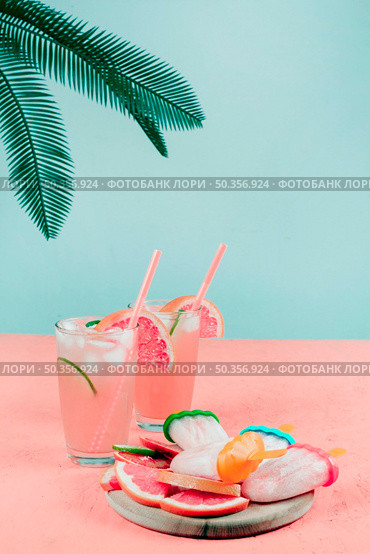 palm leaves grapefruit cocktail glasses popsicles coral desk against teal background. Стоковое фото, агентство Ingram Publishing / Фотобанк Лори