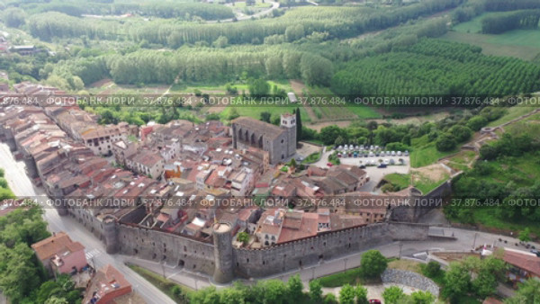 Panoramic aerial view of medieval walled village of Hostalric with reddish tiled roofs of residential buildings on summer day, Catalonia, Spain. Стоковое видео, видеограф Яков Филимонов / Фотобанк Лори