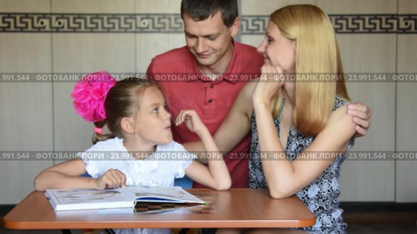 Папа и мама с любовью смотрят на свою дочку первоклассницу которая делает уроки. Стоковое видео, видеограф Иванов Алексей / Фотобанк Лори