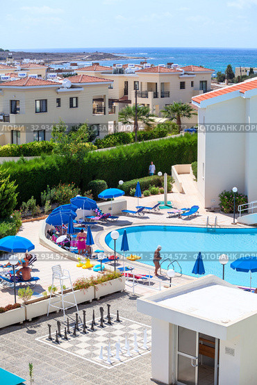 PAPHOS, CYPRUS-CIRCA SEP, 2013: Buildings and poolside of Kissos hotel with resting people. It is a family resort and three stars hotel located next to the Tombs of the Kings and the Paphos Lighthouse. Редакционное фото, фотограф Кекяляйнен Андрей / Фотобанк Лори