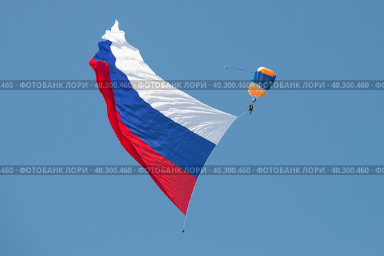Парашютист с большим российским флагом в голубом безоблачном небе. Фрагмент открытия авиационного шоу МАКС-2019. Редакционное фото, фотограф Виктор Карасев / Фотобанк Лори