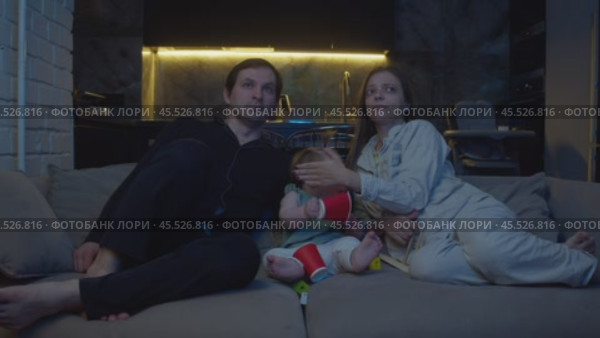 Parents shield their little daughter's eyes from information on TV that they feel is not suitable for her age. Стоковое видео, видеограф Strunov David / Фотобанк Лори