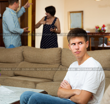 Parents swear among themselves. Offended son sits on a sofa. Стоковое фото, фотограф Яков Филимонов / Фотобанк Лори