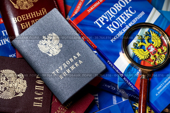 Паспорт, военный билет и трудовая книжка сотрудника, Трудовой кодекс Российской Федерации лежат на столе в отделе кадров предприятия (2023 год). Редакционное фото, фотограф Николай Винокуров / Фотобанк Лори