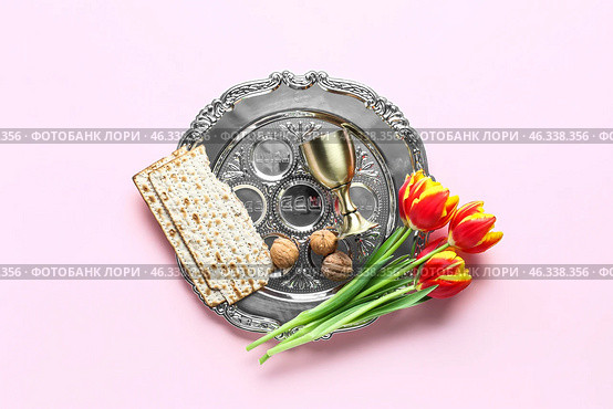 Passover Seder plate, flatbread matza, walnuts, flowers and cup on pink background. Стоковое фото, фотограф Pixel_shot / Фотобанк Лори