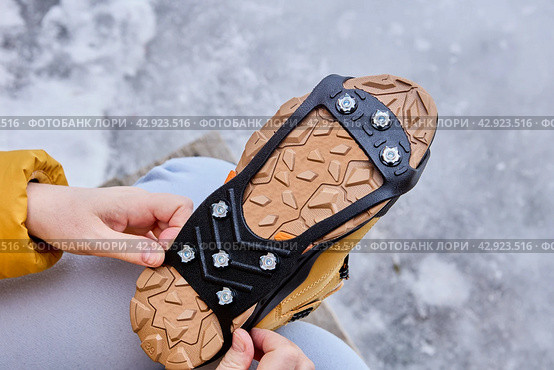 Pedestrian putting cleats on his shoes for extra traction during a winter walk during icy conditions. Стоковое фото, фотограф Владимир Григорьев / Фотобанк Лори