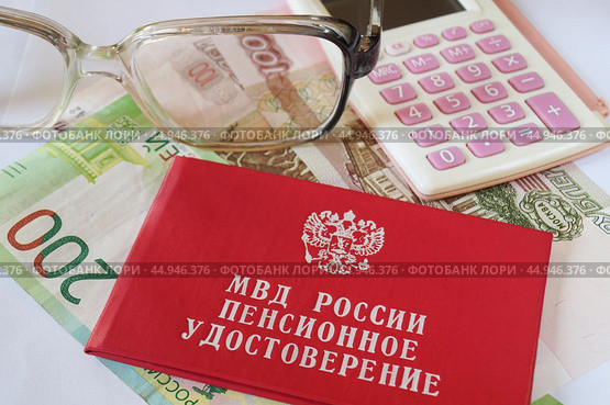 Пенсионное удостоверение МВД России и калькулятор лежат на денежных купюрах. Стоковое фото, фотограф Сергей Овчинников / Фотобанк Лори
