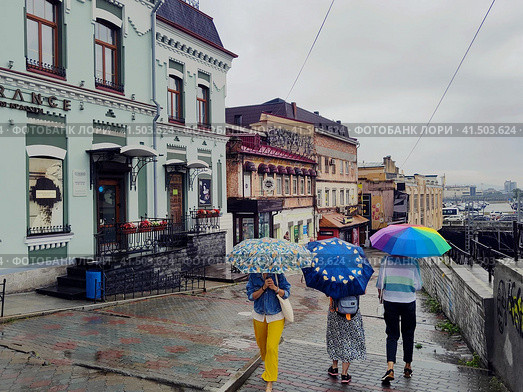 People with bright umbrellas walk through city with old buildings. Rain weather in summer. Beautiful architecture. Admiral Fokin Street, descent to Flower Passage. Vladivostok, Russia, August 10, 2023. Редакционное фото, фотограф Ирина / Фотобанк Лори