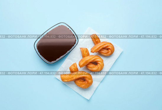 Пергамент с вкусными чуррос и соусом из расплавленного шоколада на цветном фоне. Стоковое фото, фотограф Pixel_shot / Фотобанк Лори
