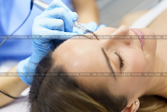 Permanent make-up for eyelashes of beautiful woman in a beauty salon. Close-up of beautician doing tattooing eyelashes. Micropigmentation treatment.. Permanent make-up for eyelashes of beautiful woman in a beauty salon. Micropigmentation treatment. Стоковое фото, агентство Ingram Publishing / Фотобанк Лори