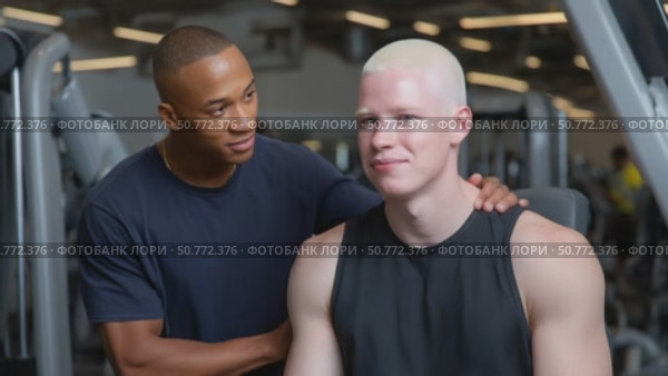 Personal trainer supporting albino athlete during workout. Стоковое AI-видео, аниматор Юрий Поздников / Фотобанк Лори