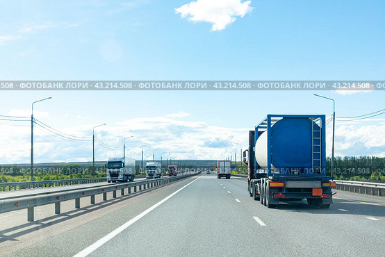 Petrol cargo truck driving on highway hauling oil products. Fuel delivery transportation and logistics concept on a sunny summer evening. Compressed gas carrier truck rear view on a highway. Стоковое фото, фотограф Ирина Михайличенко / Фотобанк Лори