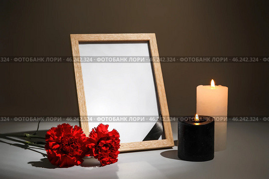 Photo frame with carnation flowers and candles on table against dark background. Стоковое фото, фотограф Pixel_shot / Фотобанк Лори