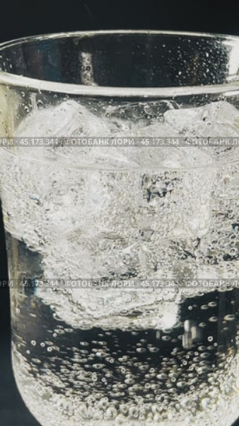 Pieces of ice float in a clear glass in a carbonated drink. Close-up shooting. Стоковое видео, видеограф Ярославский Максим / Фотобанк Лори