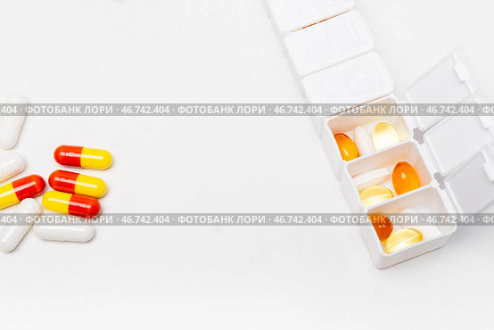 Pillbox by days of the week with fish oil and various pills, on a white background. pillbox for keeping up with your vitamin regimen. Стоковое фото, фотограф Кашапова Эльвира / Фотобанк Лори