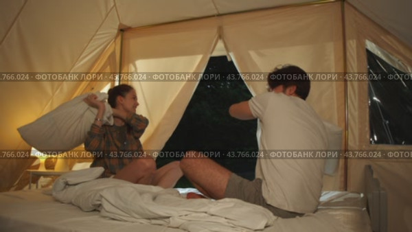 Pillow fight. The lovers are playing around in their tent at the campsite. Стоковое видео, видеограф Strunov David / Фотобанк Лори