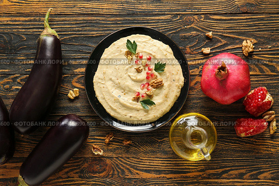 Plate of tasty baba ghanoush with ingredients on wooden background. Стоковое фото, фотограф Pixel_shot / Фотобанк Лори