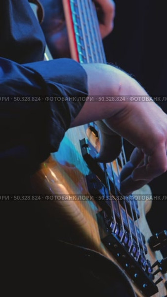 Playing a five-string bass guitar close-up. Hands professionally picking and pulling strings. The deck of the bass guitar is made of wood. Slow motion. Стоковое видео, видеограф Воловодов Владимир / Фотобанк Лори