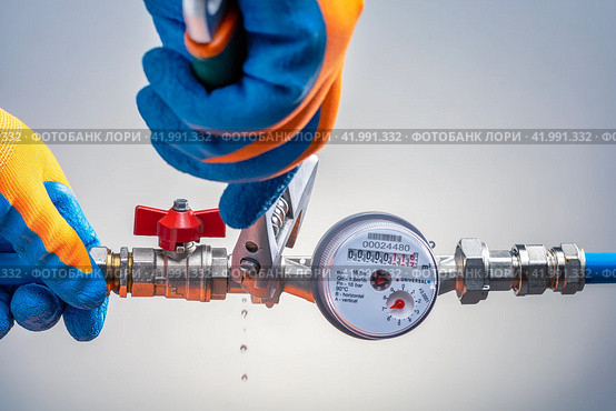 Plumber Repairing Water Pipe, слесарь с ключом ремонтирует повреждённый водопровод, течь воды из лопнувшей трубы. Стоковое фото, фотограф Сергей Чуйко / Фотобанк Лори
