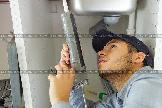 plumber sealing sink with silicone. Стоковое фото, агентство Ingram Publishing / Фотобанк Лори