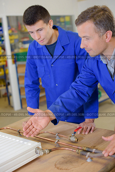 Plumber showing radiator to trainee. Стоковое фото, агентство Ingram Publishing / Фотобанк Лори