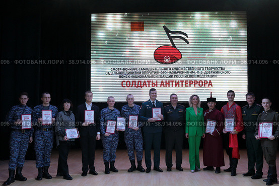 Победители первого этапа творческого конкурса "Солдаты антитеррора", военнослужащие играют на гитарах на фоне фотографий из СВО (2023 год). Редакционное фото, фотограф Дмитрий Неумоин / Фотобанк Лори