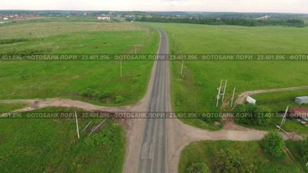Полет вдоль загородной асфальтовой дороги среди зеленых лугов. Московская область. Курово (2016 год). Стоковое видео, видеограф Кекяляйнен Андрей / Фотобанк Лори