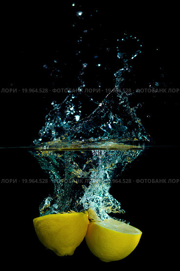 Половинки лимона брошены в воду на черном фоне. Стоковое фото, фотограф Иван Карпов / Фотобанк Лори