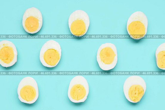 Половинки вкусных отваренных яиц на голубом фоне. Стоковое фото, фотограф Pixel_shot / Фотобанк Лори