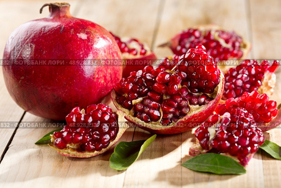 pomegranate with leafs on wooden table. Стоковое фото, агентство Ingram Publishing / Фотобанк Лори
