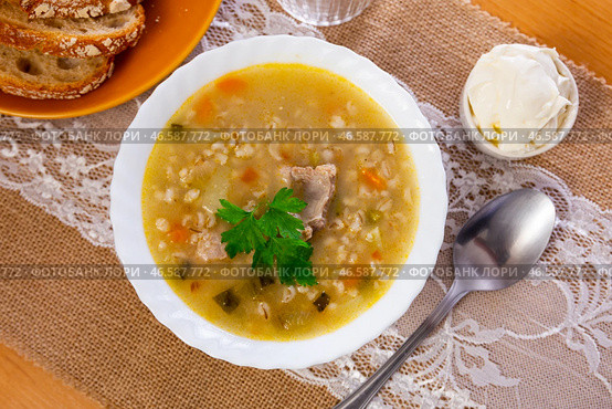 Popular dish of Russian cuisine is pickle soup with meat, cooked on basis of pickled cucumbers and pearl barley or rice, decorated with sprig of parsley. Стоковое фото, фотограф Яков Филимонов / Фотобанк Лори
