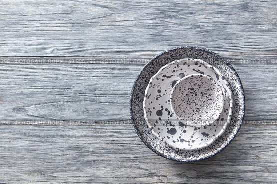 Porcelain gray bowls and plates on a gray wooden table with place for text. Colorful ceramic vintage handmade dishes. Flat lay. Decorative pottery - bowls, plates covered with glazed on a gray wooden background. Top view of traditional handcrafted. Стоковое фото, агентство Ingram Publishing / Фотобанк Лори