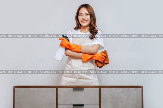 Portrait happy young pretty woman in apron and rubber gloves holding a spray bottle with cloth preparing to cleaning, smile and looking to camera, copy space. Стоковое фото, агентство Ingram Publishing / Фотобанк Лори