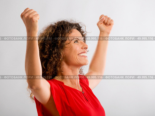 Portrait of a happy middle aged brunette with arms up expressing victory. Стоковое фото, агентство Ingram Publishing / Фотобанк Лори