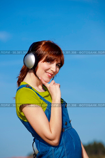 Portrait of a happy woman listen music over a beautiful blue sky. Стоковое фото, агентство Ingram Publishing / Фотобанк Лори