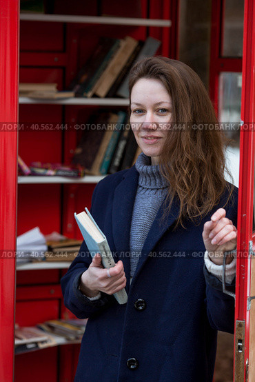 Portrait of a young woman over 30 years old with a book in her hands, a girl took a book from a street library. Modern lifestyle, reading books and education. Стоковое фото, фотограф Photojuli / Фотобанк Лори