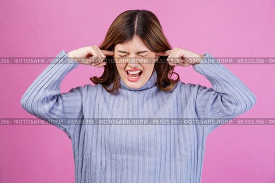 Portrait of Annoyed woman sticking plug fingers in ears not listening to loud noise sound isolated over pink background. Refuse hear avoid stress feel ear pain ache concept. Стоковое фото, агентство Ingram Publishing / Фотобанк Лори