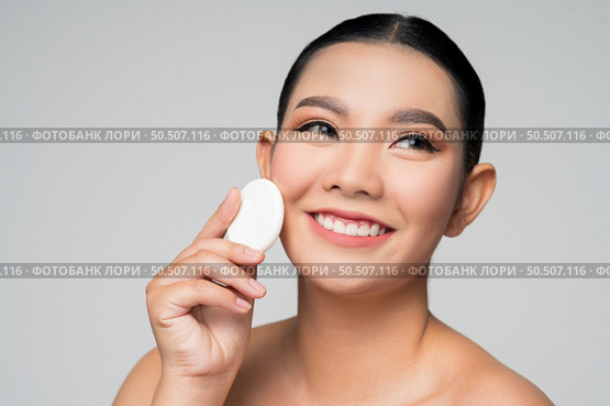 Portrait of Beautiful Asian woman holding foundation or cushion sponge puff. Skin care healthy hair and skin close up face beauty isolated over background. Cosmetology and Spa concept. Стоковое фото, агентство Ingram Publishing / Фотобанк Лори