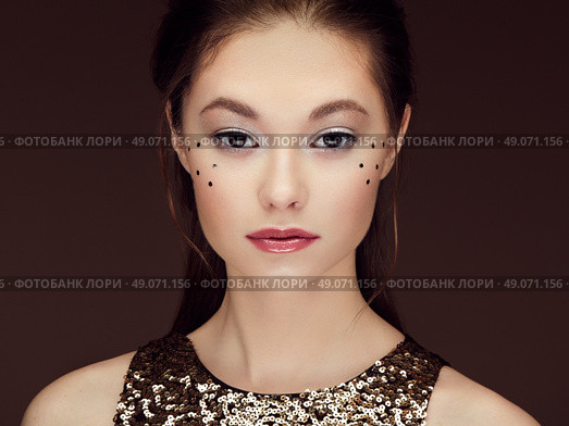 Portrait of beautiful young woman in a shiny golden dress. Brunette girl. Perfect make-up. Freckles. Стоковое фото, агентство Ingram Publishing / Фотобанк Лори