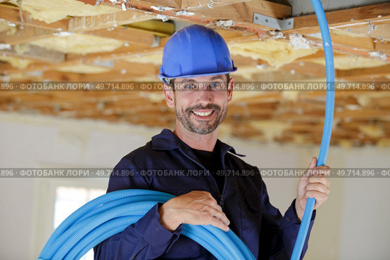 portrait of builder holding reel of blue cable. Стоковое фото, агентство Ingram Publishing / Фотобанк Лори