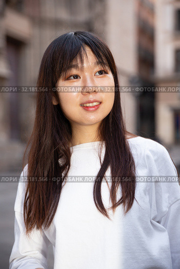 Portrait of cheerful young chinese longhaired woman standing on a city street. Стоковое фото, фотограф Яков Филимонов / Фотобанк Лори