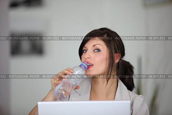 portrait of classy brunette working on laptop with bottle of water. Стоковое фото, агентство Ingram Publishing / Фотобанк Лори