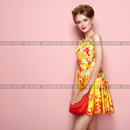 Portrait of Fashion Young woman in Floral Dress. Female Model in Stylish Spring Summer Outfit. Girl Posing on a Pink Background. Stylish Hairstyle. Blonde Lady with Red Handbag. Стоковое фото, агентство Ingram Publishing / Фотобанк Лори