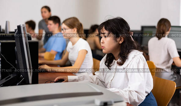 Portrait of fifteen-year-old schoolgirl studying at computer in class at an informatics lesson with classmates. Стоковое фото, фотограф Яков Филимонов / Фотобанк Лори