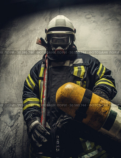 Portrait of firefighter in safety uniform holding yellow oxigen tank. Стоковое фото, агентство Ingram Publishing / Фотобанк Лори