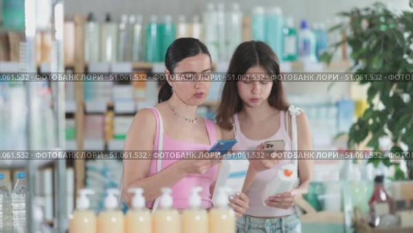 Portrait of friendly family of mother and daughter customers holding, scan QR code on label and selecting cream or skin care product in modern drugstore. Стоковое видео, видеограф Яков Филимонов / Фотобанк Лори