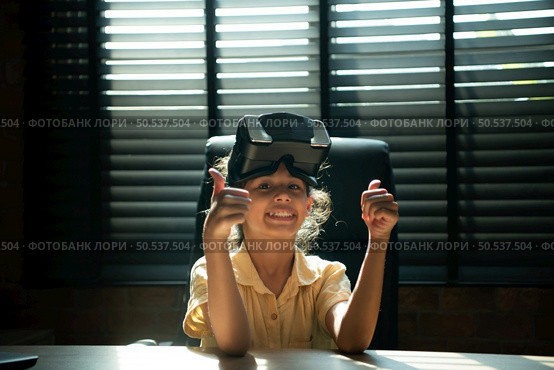 Portrait of little girl in office room of house with gestures that are expressed when playing virtual reality games. Стоковое фото, агентство Ingram Publishing / Фотобанк Лори