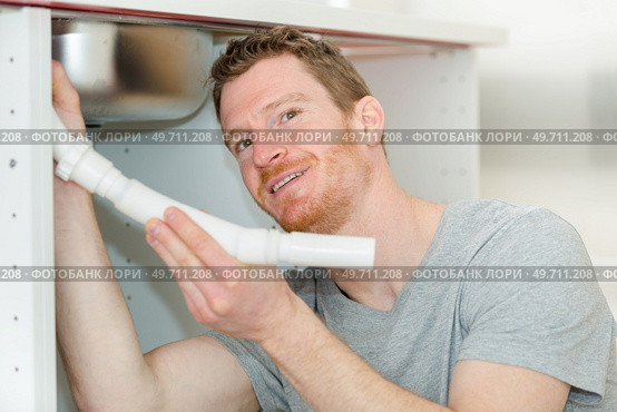 portrait of man working on sink pipework. Стоковое фото, агентство Ingram Publishing / Фотобанк Лори