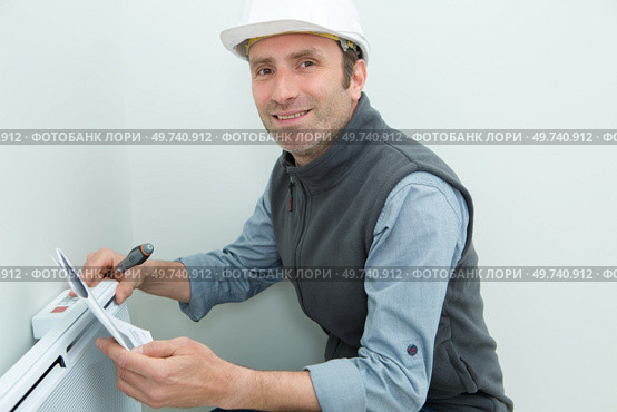 portrait of plumber fixing a radiator. Стоковое фото, агентство Ingram Publishing / Фотобанк Лори